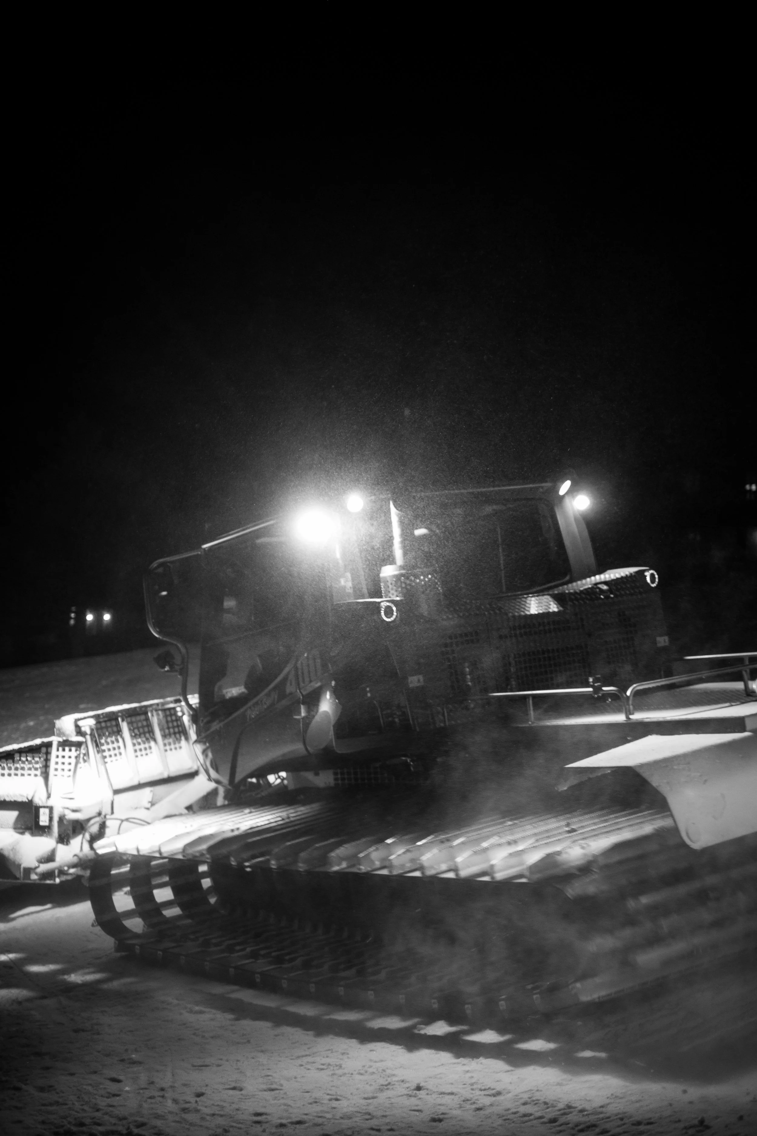 Ein Schneemobil bei Nacht, beleuchtet durch Scheinwerfer.